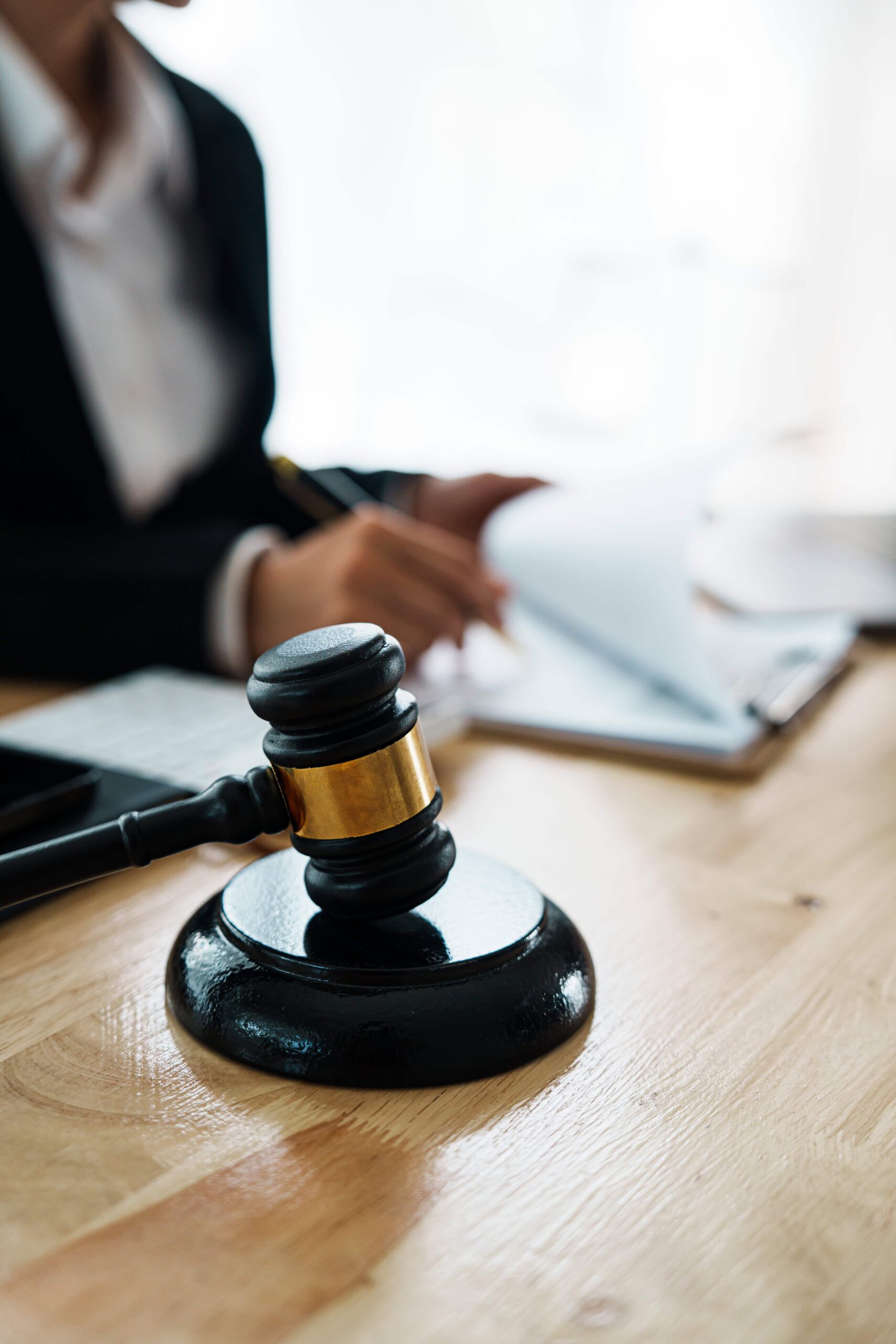 A professional lawyer advises a client in a legal office with gavel sitting on brown desk